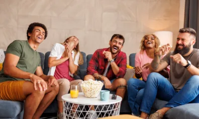 friends laughing while watching tv at home jpg