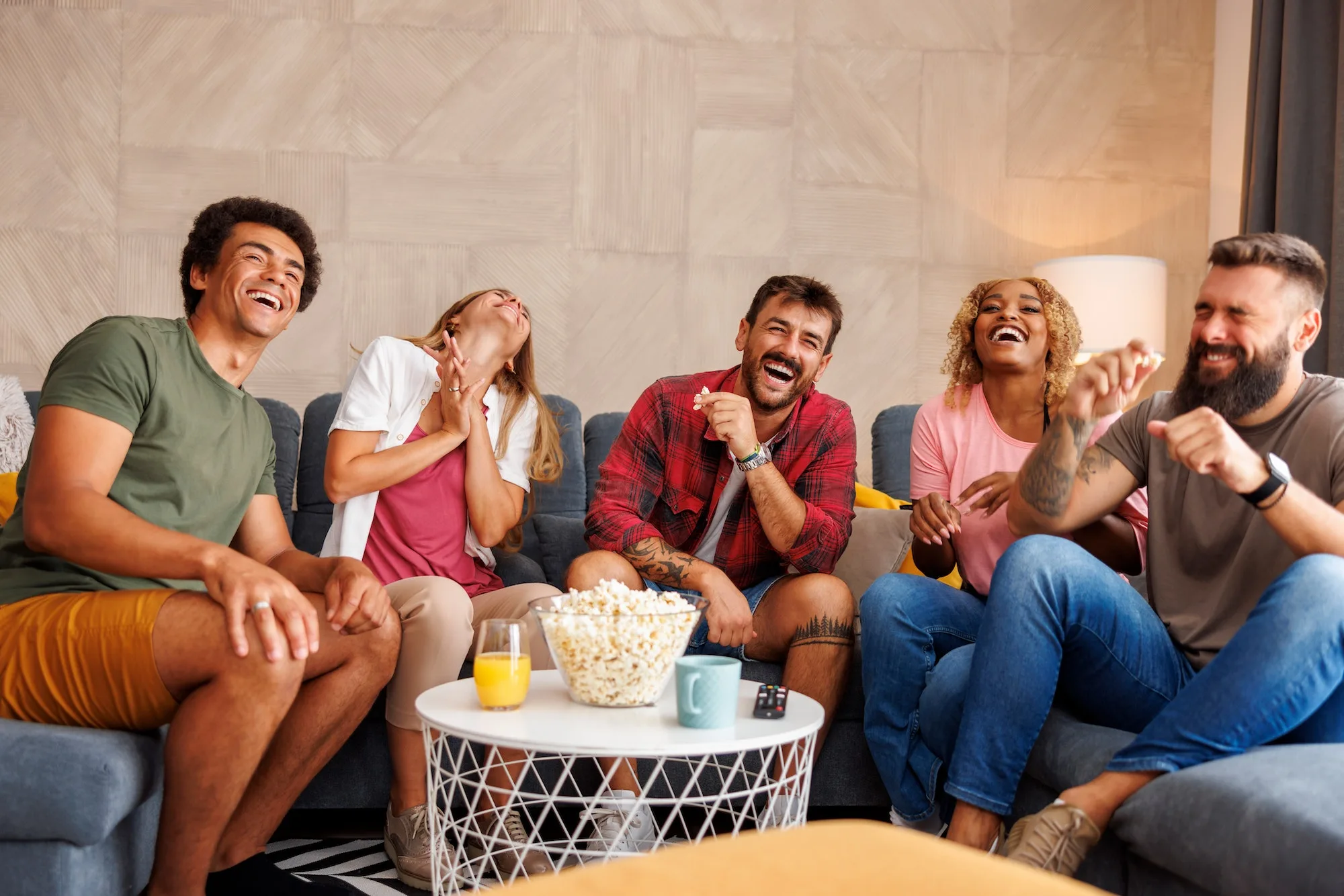 friends laughing while watching tv at home jpg